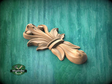 Load image into Gallery viewer, A wooden decorative piece with an intricate, flowing design is displayed against a green background.