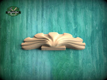 Load image into Gallery viewer, A wooden carving of a stylized flower or plant is displayed against a green textured background.