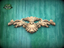 Load image into Gallery viewer, A decorative wooden carving with intricate floral and leaf-like patterns is displayed against a green wooden background.