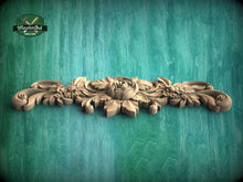 Load image into Gallery viewer, A decorative wooden carving with intricate floral designs is displayed against a green background.