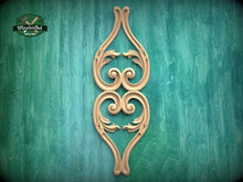 Load image into Gallery viewer, a decorative wooden carving of a stylized floral design on a green background.