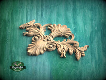 Load image into Gallery viewer, A decorative wooden carving with intricate floral and leaf-like patterns is displayed against a green wooden background.