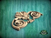Load image into Gallery viewer, A decorative wooden carving with an intricate, swirling design is displayed against a green background.