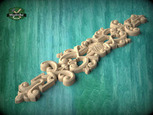 Load image into Gallery viewer, A decorative wooden carving with intricate floral and scrollwork designs is displayed against a teal background.
