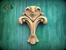 Load image into Gallery viewer, a wooden carving of a stylized flower or plant on a green background.