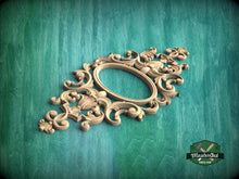 Load image into Gallery viewer, an ornate, carved wooden frame with intricate scrollwork and floral designs, set against a green background.