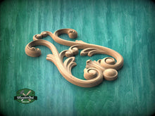 Load image into Gallery viewer, A wooden carving with intricate scrollwork and floral designs is displayed against a teal background.