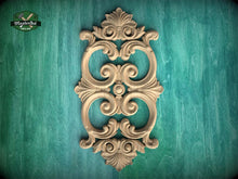 Load image into Gallery viewer, an ornate, carved wooden piece with intricate scrollwork and floral designs, set against a green wooden background.