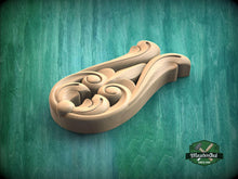 Load image into Gallery viewer, A wooden carving with intricate scrollwork is displayed against a green background.