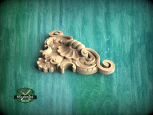 Load image into Gallery viewer, A decorative wooden carving in the shape of a flower or leaf, placed on a green textured background.