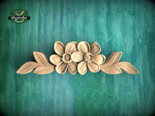 Load image into Gallery viewer, a wood carving of flowers on a green background