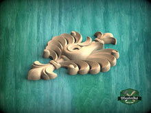 Load image into Gallery viewer, A wooden carving of a stylized flower or plant with intricate, curved petals is displayed against a green background.