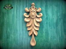 Load image into Gallery viewer, A decorative wooden carving of a leaf-like design is displayed against a green textured background.
