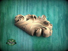 Load image into Gallery viewer, A wooden carving of a stylized leaf or flower design is displayed against a green background.