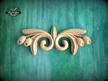 Load image into Gallery viewer, A decorative wooden carving in the shape of a stylized flower or leaf design is displayed against a green textured background.