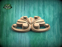 Load image into Gallery viewer, A wooden carving of a stylized flower or floral design is displayed against a teal-colored background.