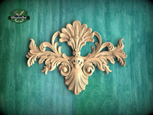 Load image into Gallery viewer, an ornate, carved wooden design with intricate scrollwork and floral elements, set against a green background.