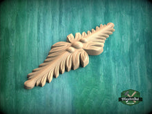 Load image into Gallery viewer, A wooden carving of a leaf-like design is displayed against a green background.
