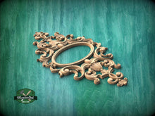 Load image into Gallery viewer, an ornate, carved wooden frame with intricate designs and patterns, set against a green wooden background.