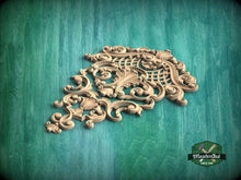 Load image into Gallery viewer, an ornate, carved wooden piece with intricate scrollwork and floral designs, set against a green background.