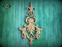 Load image into Gallery viewer, an ornate, carved wooden piece with intricate, decorative elements, such as leaves and flowers, mounted on a green wooden background.