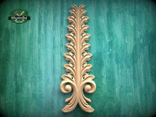 Load image into Gallery viewer, a decorative wooden leaf-like object with a vertical, ornate design on a green background.