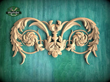 Load image into Gallery viewer, a decorative wooden carving with intricate floral and leaf-like patterns, set against a green background.