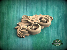 Load image into Gallery viewer, A carved wooden ornament with a floral design is displayed against a green background.