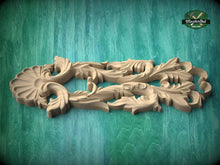 Load image into Gallery viewer, A carved wooden piece with intricate floral designs, displayed against a green background.