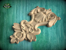 Load image into Gallery viewer, A wooden carving with intricate floral and leaf designs is displayed against a green background.