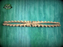 Load image into Gallery viewer, A decorative wooden carving with an intricate floral design is displayed against a textured green background.
