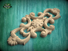 Load image into Gallery viewer, A decorative wooden carving with intricate floral and scroll designs is displayed against a green background.