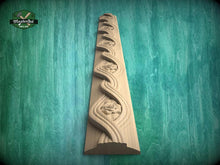 Load image into Gallery viewer, A wooden carving of a floral design on a green background.