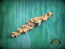 Load image into Gallery viewer, a wooden carving of a flower on a green background