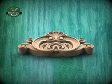 Load image into Gallery viewer, A wooden carving with intricate scrollwork and floral designs is displayed against a green background.