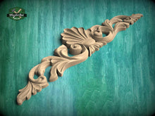 Load image into Gallery viewer, A decorative wooden carving with intricate floral and scrollwork designs is displayed against a teal background.