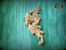 Load image into Gallery viewer, A decorative wooden carving with an intricate, flowing design is displayed against a teal-colored background.
