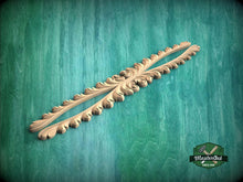 Load image into Gallery viewer, A decorative wooden piece with an intricate design, resting on a green textured background.