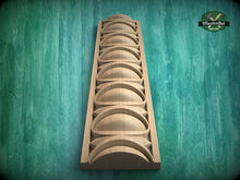 Load image into Gallery viewer, A wooden carving with a series of curved shapes arranged in a vertical line, set against a green background.