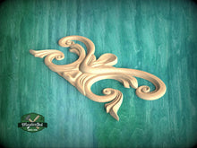 Load image into Gallery viewer, A wooden carving of an ornate, curving design is displayed against a teal background.