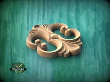 Load image into Gallery viewer, A wooden carving of a stylized floral design is displayed against a green background.