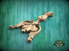 Load image into Gallery viewer, A wooden carving with an ornate, decorative design is displayed against a green background.