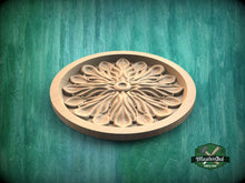Load image into Gallery viewer, A wooden ornamental piece with a floral design, placed on a green textured background.