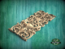 Load image into Gallery viewer, A decorative wooden carving with intricate scrollwork and floral patterns is displayed against a green background.