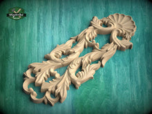 Load image into Gallery viewer, A wooden carving with intricate floral and leaf-like designs is displayed against a green background.