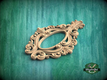 Load image into Gallery viewer, A decorative wooden frame with intricate scrollwork and floral patterns is displayed against a green wooden background.