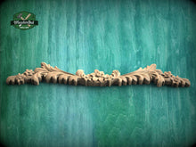 Load image into Gallery viewer, a wooden carving of a flower on a green background