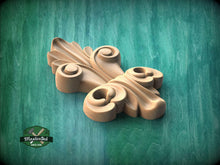 Load image into Gallery viewer, A wooden ornamental piece with a decorative design, resting on a green textured background.