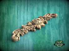 Load image into Gallery viewer, A decorative wooden carving with intricate floral and leaf designs is displayed against a green background.