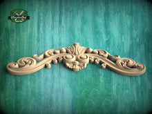 Load image into Gallery viewer, A decorative wooden carving with intricate scrollwork and floral elements is displayed against a green wooden background.